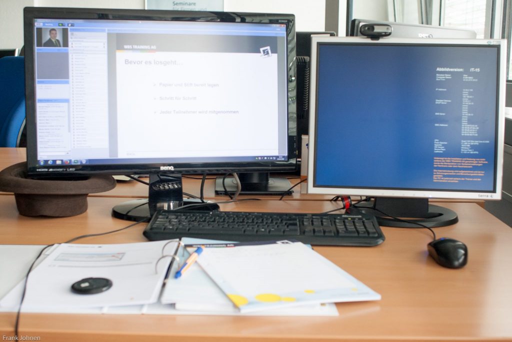 Das Bild zeigt einen Computer mit 2 Bildschirmen auf einem Schreibtisch. Die Umschulung zum Fachinformatiker Systemintegration findet am PC in einem virtuellen Klassenzimmer statt.